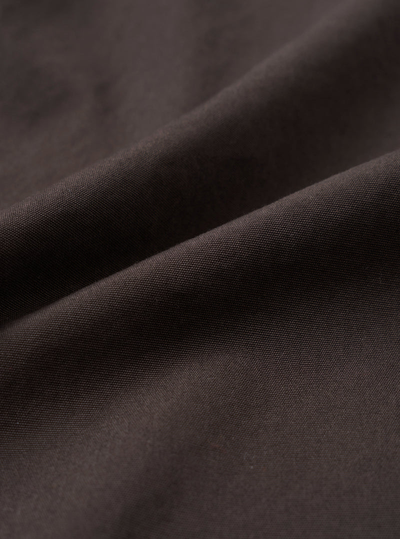 A close-up fabric swatch image of the Brown Micro Canvas Oxford Pant set against a solid white background, displaying the tight weave, fine surface texture, and natural shade of the brown cotton canvas material.