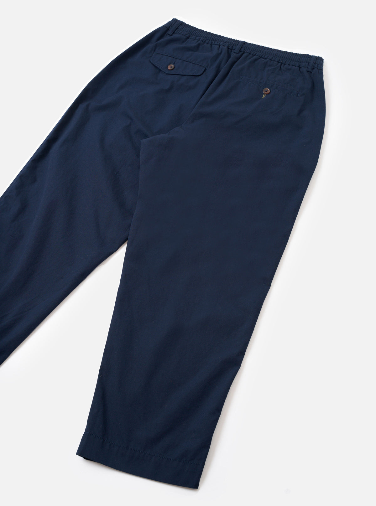 Rear view shot of the Navy Micro Canvas Oxford Pant presented against a clean white studio background. The shot highlights the back pocket layout, loose trouser silhouette, and solid dark navy cotton micro-canvas fabric.