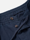 Close-up detail shot of the Navy Micro Canvas Oxford Pant set on a plain studio background. The image highlights the adjustable drawstring waist, front pleats, slash side pockets, and fine navy blue micro-canvas weave.