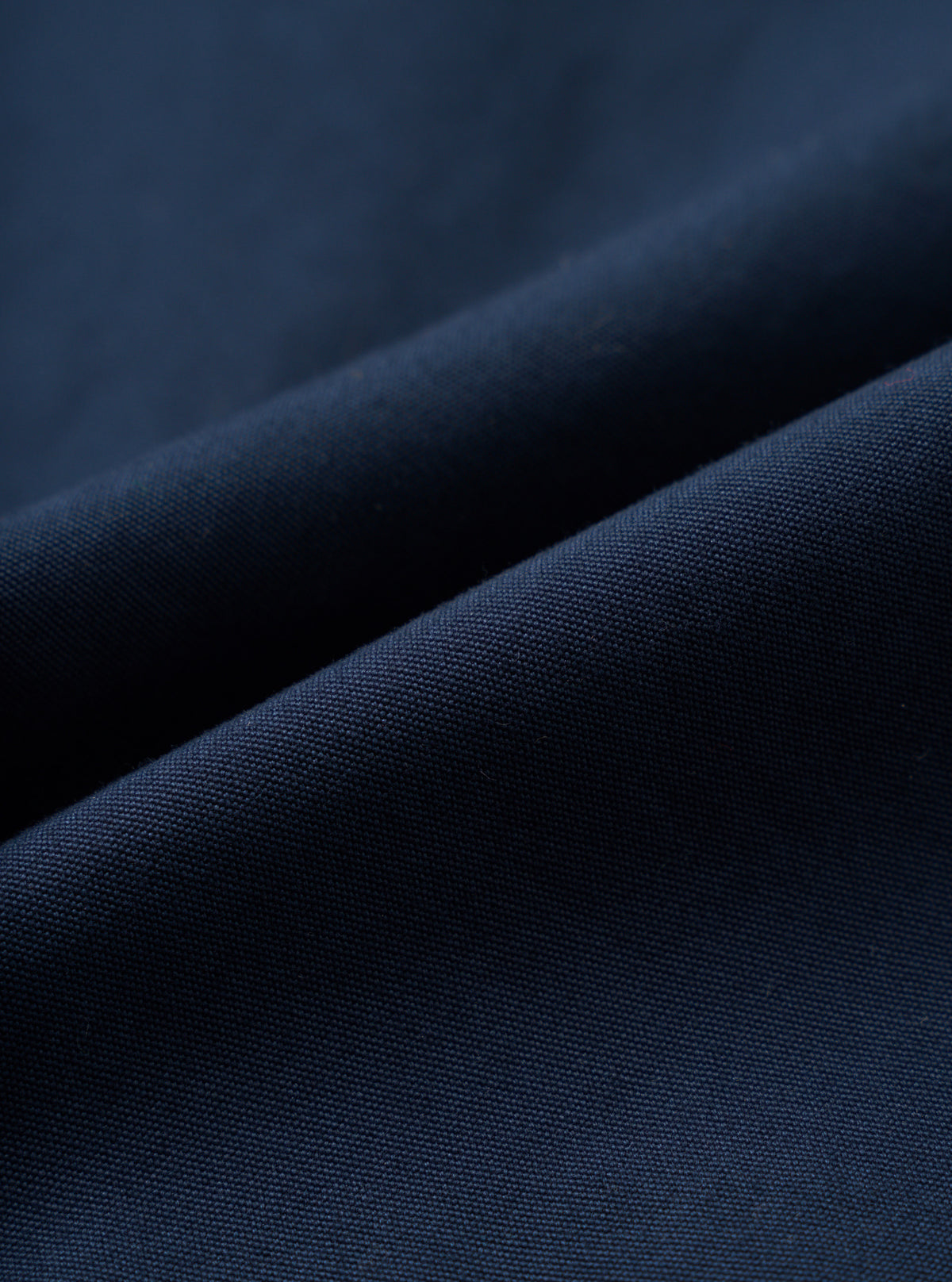 A detailed fabric swatch photograph of the Navy Micro Canvas Oxford Pant displayed on a plain white background, showcasing the rich navy blue color and smooth micro-canvas texture of the cotton fabric.
