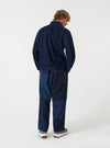Back view of a model wearing the Navy Patchwork Twill Oxford Pant against a clean studio background, showcasing the relaxed tailoring, waistband, and textured navy patchwork twill material.