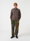 Full-length front view of a model wearing the Olive Patchwork Twill Oxford Pant in a studio setting with a neutral background, highlighting the loose pleated fit and olive cotton twill texture.