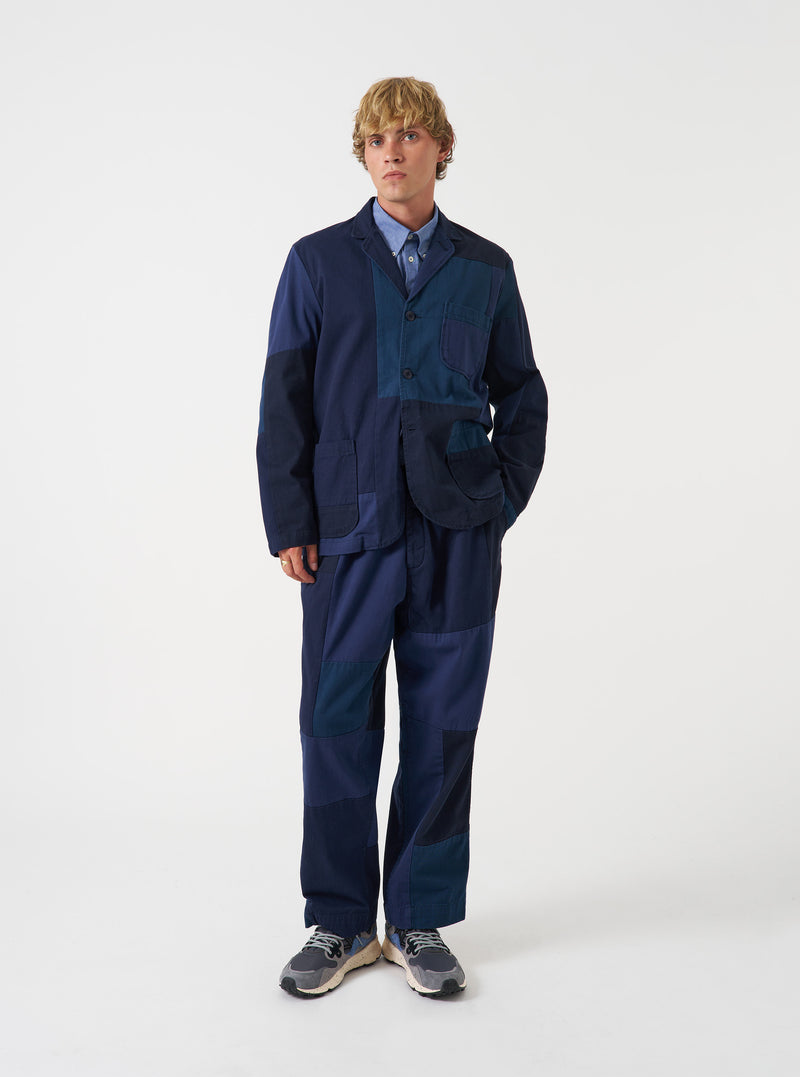 Front view of a model wearing the Navy Patchwork Twill Three Button Jacket in a minimalist studio setting, showcasing the tailored lapels, three-button closure, and deep navy twill cotton.