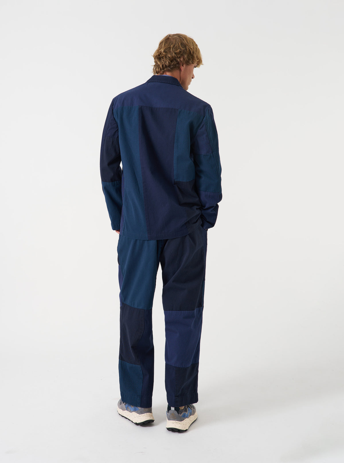 Back view of a model wearing the Navy Patchwork Twill Three Button Jacket against a plain white background, emphasizing the structured shoulder seam line and navy cotton twill paneling.