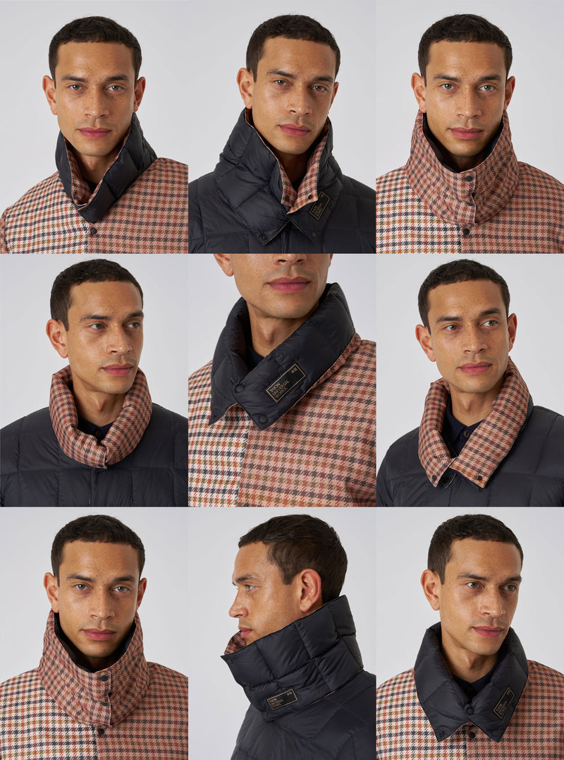 A model showcases the TAION x Universal Works Reversible Black Military Line Neck Warmer. The neck warmer is reversible, featuring black quilted nylon on one side and a brown houndstooth pattern on the other.
