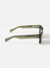 Three-quarter angle studio view of the A. SOCIETY x Universal Works Olive Hollywood Sunglasses on a light white background, showcasing the rich olive frame color, sleek curves, and dark tinted lenses.