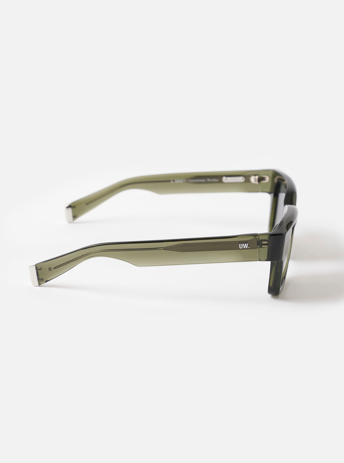 Three-quarter angle studio view of the A. SOCIETY x Universal Works Olive Hollywood Sunglasses on a light white background, showcasing the rich olive frame color, sleek curves, and dark tinted lenses.
