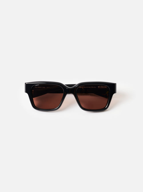 Front view product shot of the A. SOCIETY x Universal Works Black Hollywood Sunglasses set against a plain white backdrop, highlighting the thick black frame and dark tinted lenses.