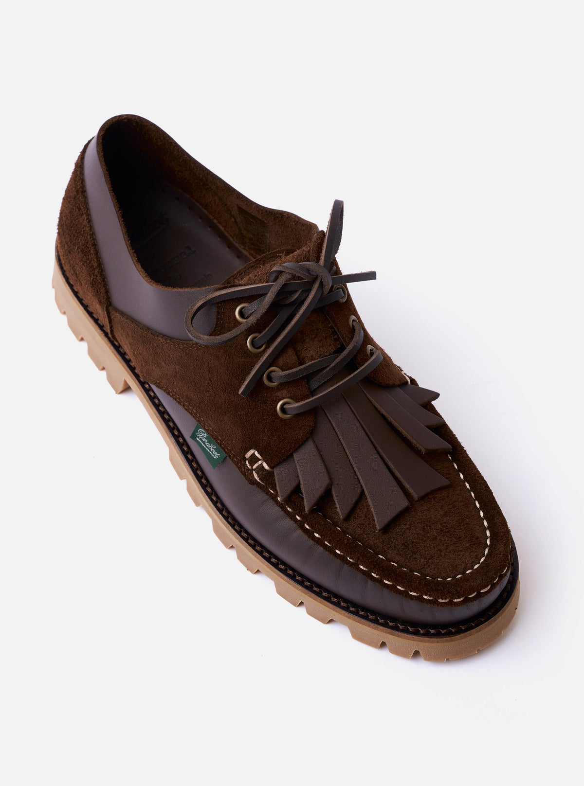 The Paraboot x Universal Works Thiers/Jannu in Café Leather/Suede is shown from a rear three-quarter angle as a flat lay against a plain white background. The image highlights the contrast between the smooth leather and textured suede-like reverse on the heel and sides, the piped seams, and the thick, vulcanised natural rubber sole. The brown leather shoe features tonal stitching and a clean, unlined construction.
