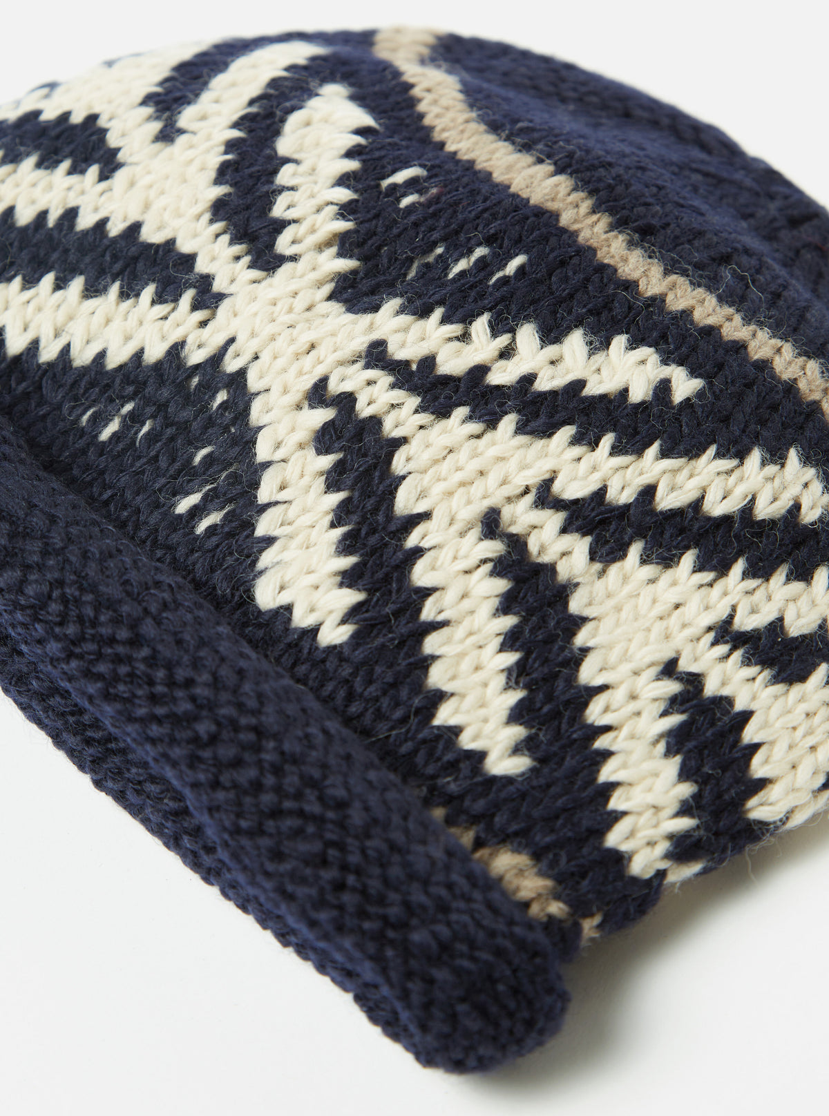 A side profile outdoor photograph of a model wearing the cableami® Navy Wool Jacquard Watch Cap, showcasing the snug fit of the dark navy knitted beanie around the head and ears.