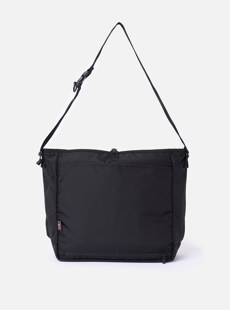 The F/CE. Black Recycled Nylon 420 re/cor Courier Shoulder Bag is shown from the back as a flat lay against a plain white background. The image highlights the wide, adjustable messenger-style shoulder strap and the smooth, technical texture of the black recycled nylon fabric.