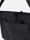The F/CE. Black Recycled Nylon 420 re/cor Courier Shoulder Bag is shown from a side-profile angle as a flat lay against a plain white background. The image highlights the bag's depth and the technical construction of the adjustable messenger-style shoulder strap, which features custom-ordered nylon tape and a metal adjustment mechanism. The black recycled nylon fabric has a subtle matte-shiny finish.