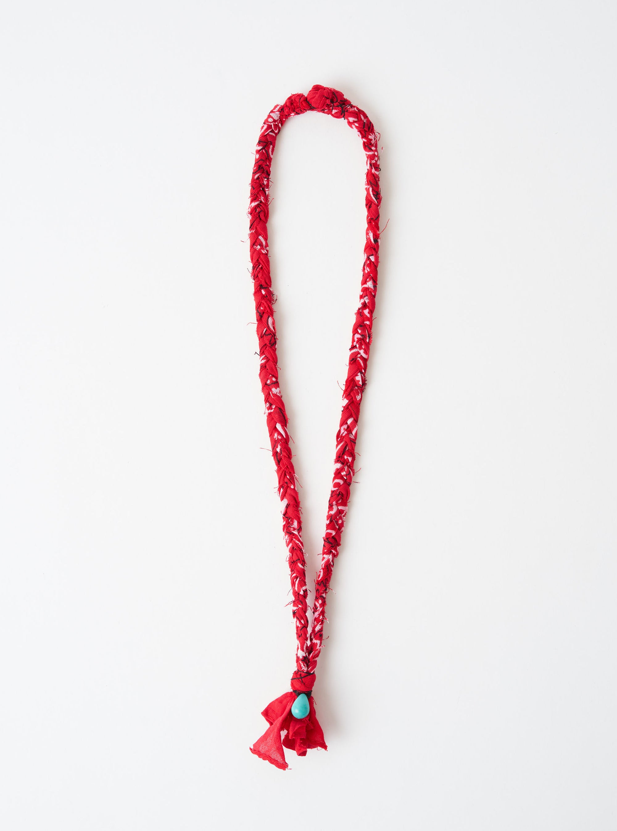 Hanami of Rome Red/Turquoise Bead Bandana Necklace No.49 on a white surface. The necklace is red with a turquoise bead at the bottom. The necklace is braided.