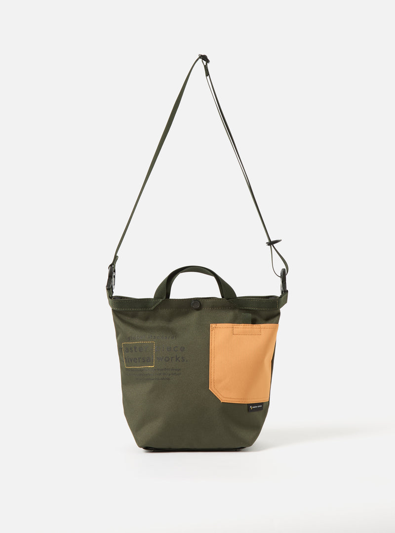 master-piece x Universal Works Olive Recycled Tech Canvas Small Tote Bag on a white background. The bag is olive with a tan pocket. It has a shoulder strap and handles.