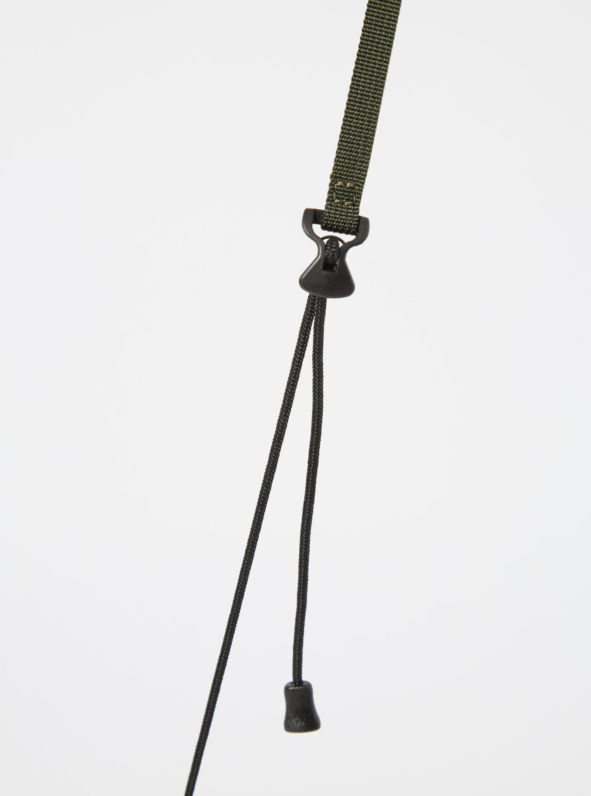 Close up of the olive strap and black drawstrings of the master-piece x Universal Works Olive Recycled Tech Canvas Sacoche against a white background.