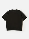 The master-piece x Universal Works Black Brush Back Sweat S/S Billy Sweat is shown from the back as a flat lay against a plain white background. The image highlights the short, cropped sleeves and the ribbed hem. A small, square collaboration patch is visible near the bottom hem on the left side.