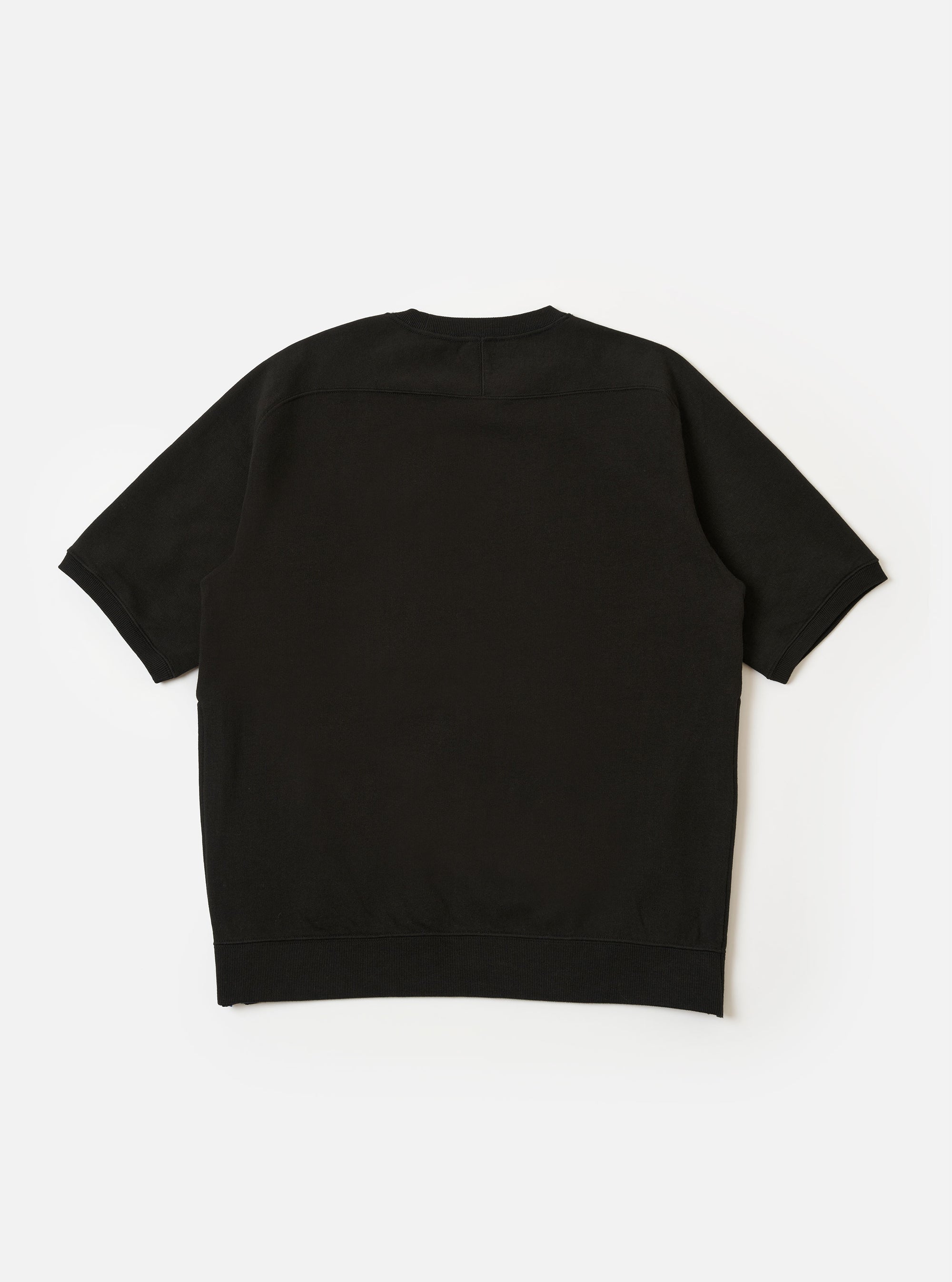 The master-piece x Universal Works Black Brush Back Sweat S/S Billy Sweat is shown from the back as a flat lay against a plain white background. The image highlights the short, cropped sleeves and the ribbed hem. A small, square collaboration patch is visible near the bottom hem on the left side.