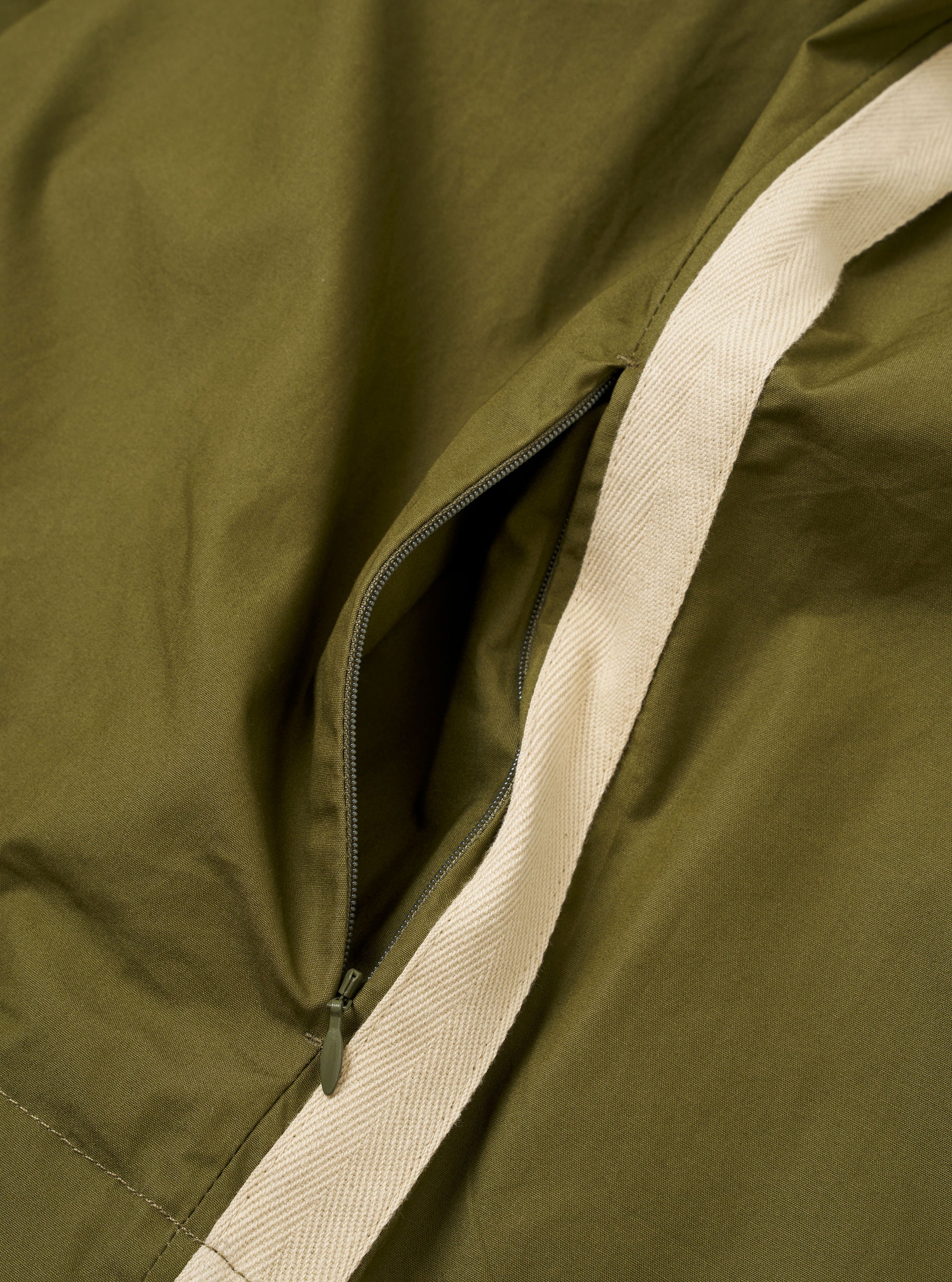 The master-piece x Universal Works Olive Recycled Poly Tech Tech Overshirt is shown in a detail view as a flat lay against a white background. The image focuses on the rear of the garment, highlighting the back yoke with a box pleat and the smooth, technical texture of the olive green recycled polytech fabric.