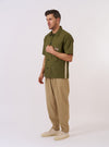 The master-piece x Universal Works Olive Recycled Poly Tech Tech Overshirt is shown as a flat lay against a plain white background. This short-sleeve overshirt features a one-piece collar, a full button-through front, and a single patch pocket on the left chest. The olive green fabric has a clean, utilitarian appearance.