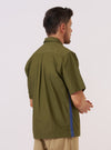 A model is wearing the master-piece x Universal Works Olive Recycled Poly Tech Tech Overshirt against a plain white background. Shown from a rear three-quarter angle, the image highlights the overshirt's boxy fit, back yoke with a central box pleat, and a straight hem. The olive green recycled polytech fabric has a smooth, utilitarian finish. No mannequin is present in the image.