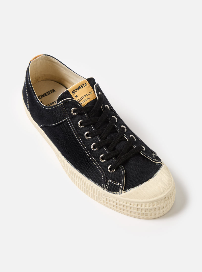 Studio shot of a Novesta for Universal Works Black Canvas Star Master shoe. The black canvas upper contrasts with the off-white rubber sole. The background is a clean, bright white.
