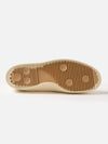Close-up of the sole of the Novesta for Universal Works Ecru Canvas Star Master shoe. The sole is brown rubber with a textured pattern. The background is a plain white surface.