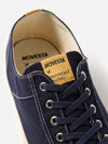 Close-up of the Novesta for Universal Works Navy Canvas Star Master shoe on a white background. Shows navy canvas, white stitching, and branded tongue.