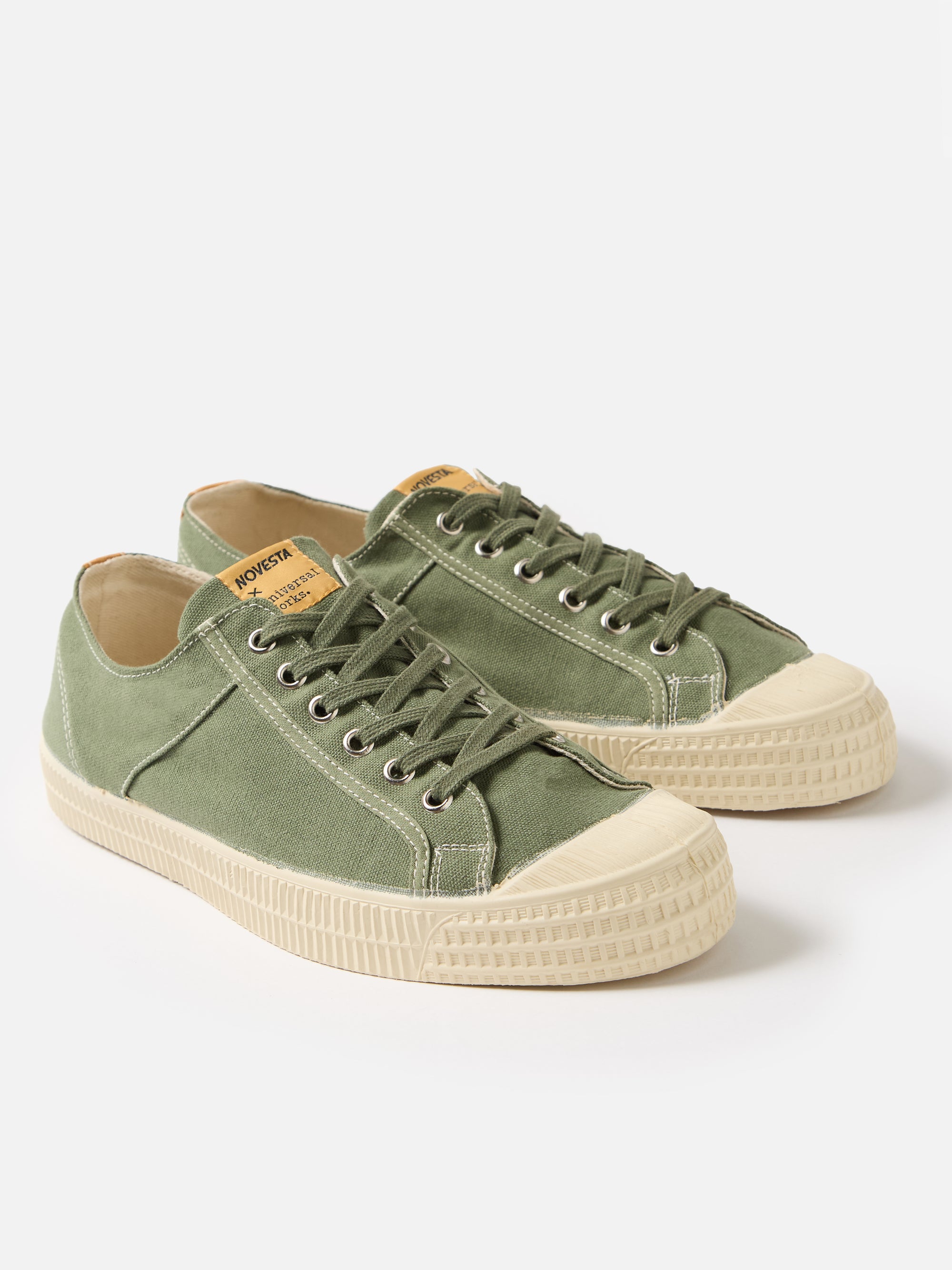 Studio shot of Novesta for Universal Works Olive Canvas Star Master sneakers. Olive canvas upper, off-white rubber sole. Simple white background.