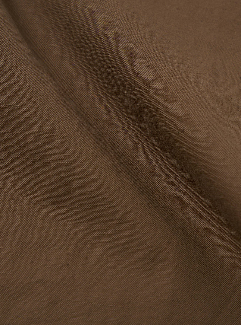 Close-up of the Khaki Linen Slub Weave Military Chino fabric. The material is a textured, earthy khaki color. The background is a simple, neutral surface.