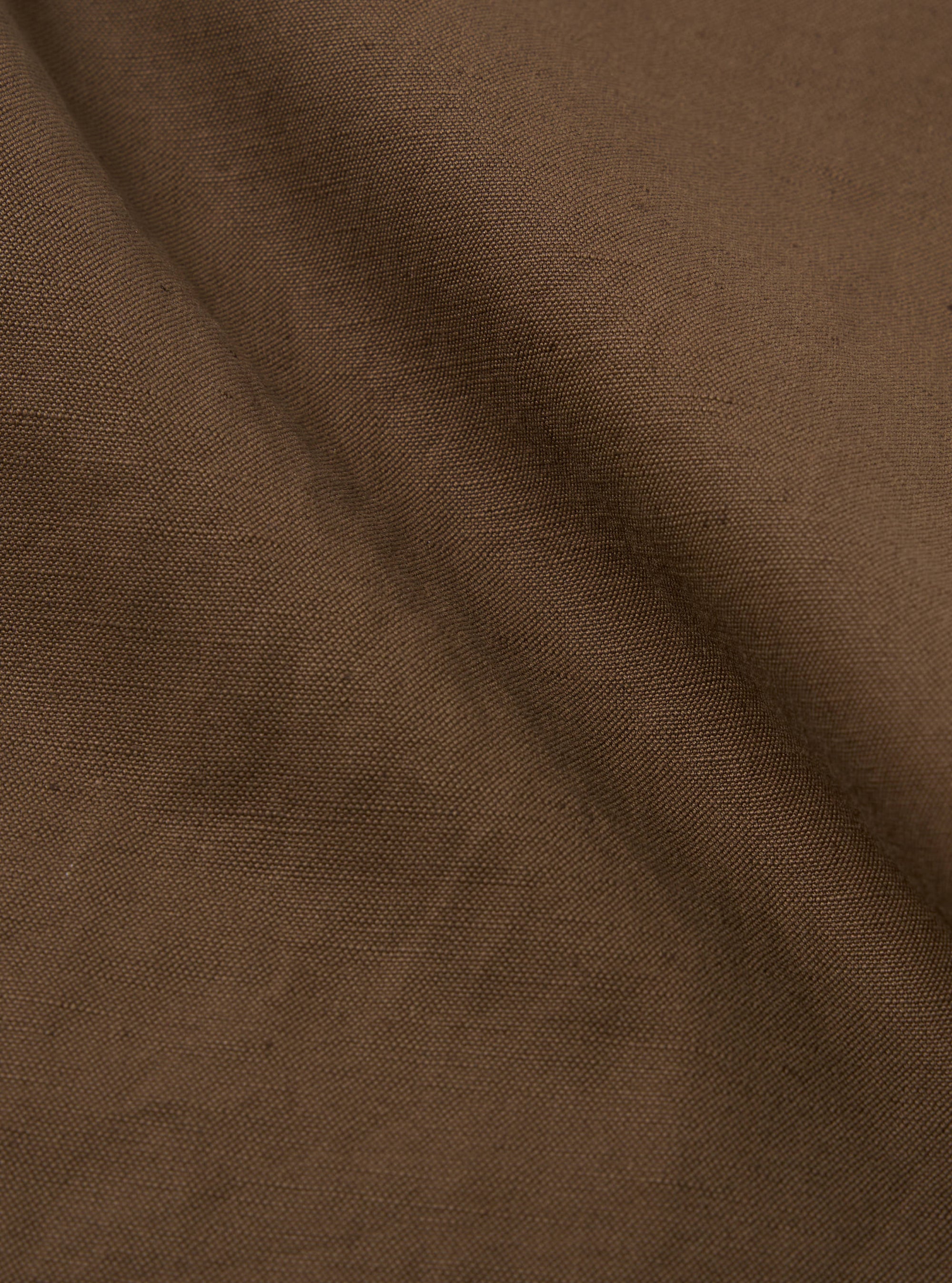 Close-up of the Khaki Linen Slub Weave Military Chino fabric. The material is a textured, earthy khaki color. The background is a simple, neutral surface.