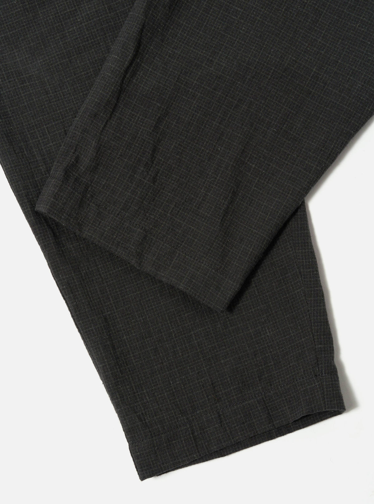 Close-up of the Charcoal Fine Linen Mix Pleated Track Pant on a white surface. The fabric shows a subtle texture and pleated details.