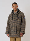 A model in a Sand Cortina Tweed Boston Parka. The parka is tweed with a black hood. The background is a plain white. The fit is relaxed and casual.