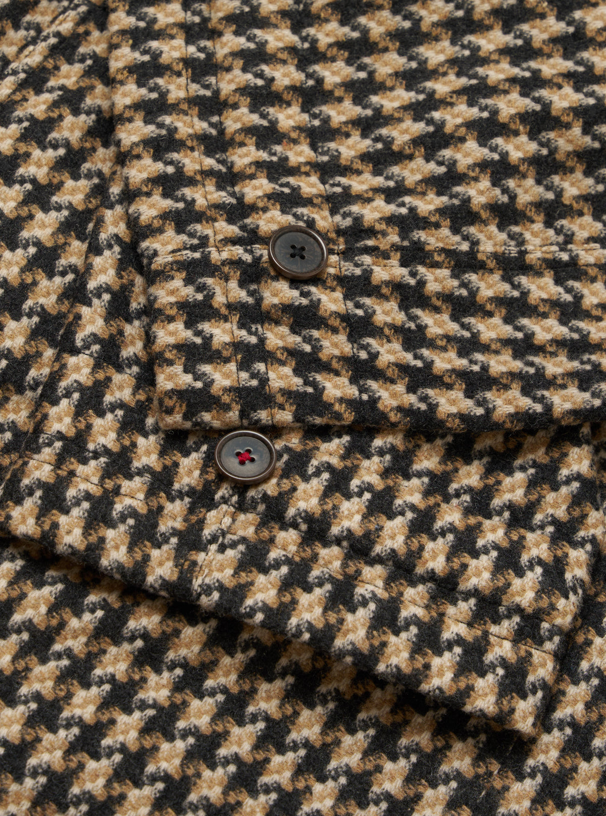 Close-up of the Sand Cortina Tweed Boston Parka, showcasing its tweed texture and button details. The background is a plain surface.