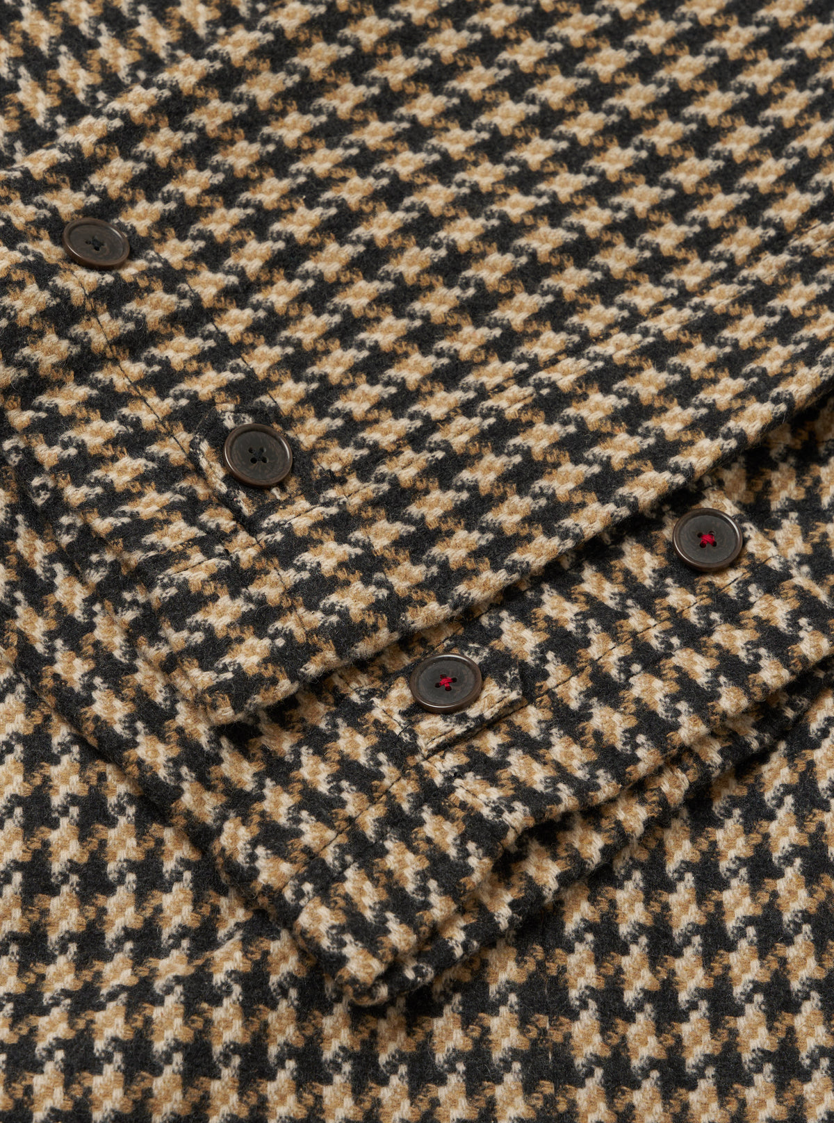 Close-up of the Sand Cortina Tweed Boston Parka showing the tweed fabric and button details. The background is a plain surface.