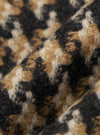 Close-up of the Sand Cortina Tweed Boston Parka fabric. The tweed has a textured feel with a mix of sand, black, and cream colors. The fabric is draped to show its texture.