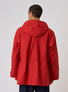 Back view of a model wearing an Orange British Wax Cotton Boston Parka. The parka is bright orange and made of wax cotton. Shot against a plain white background.