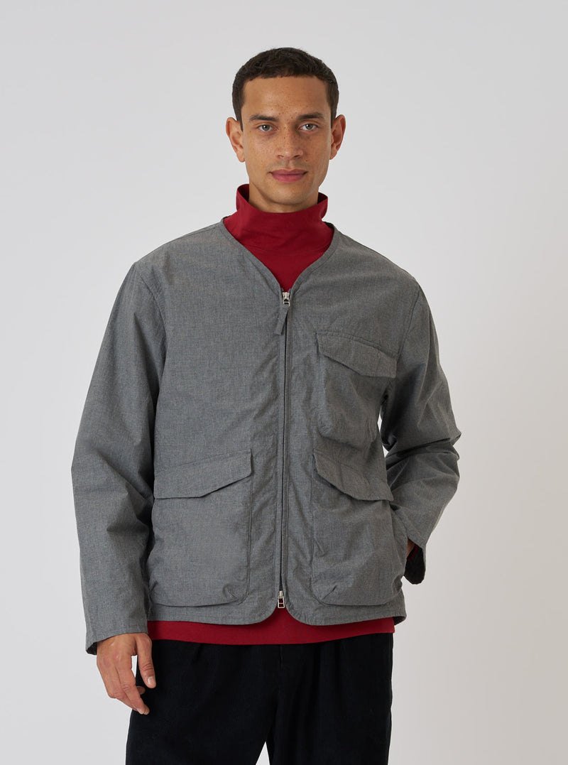 A model poses in a Charcoal Organic Chambray Parachute Liner Jacket against a white backdrop. The jacket is gray with a zip front and pockets.