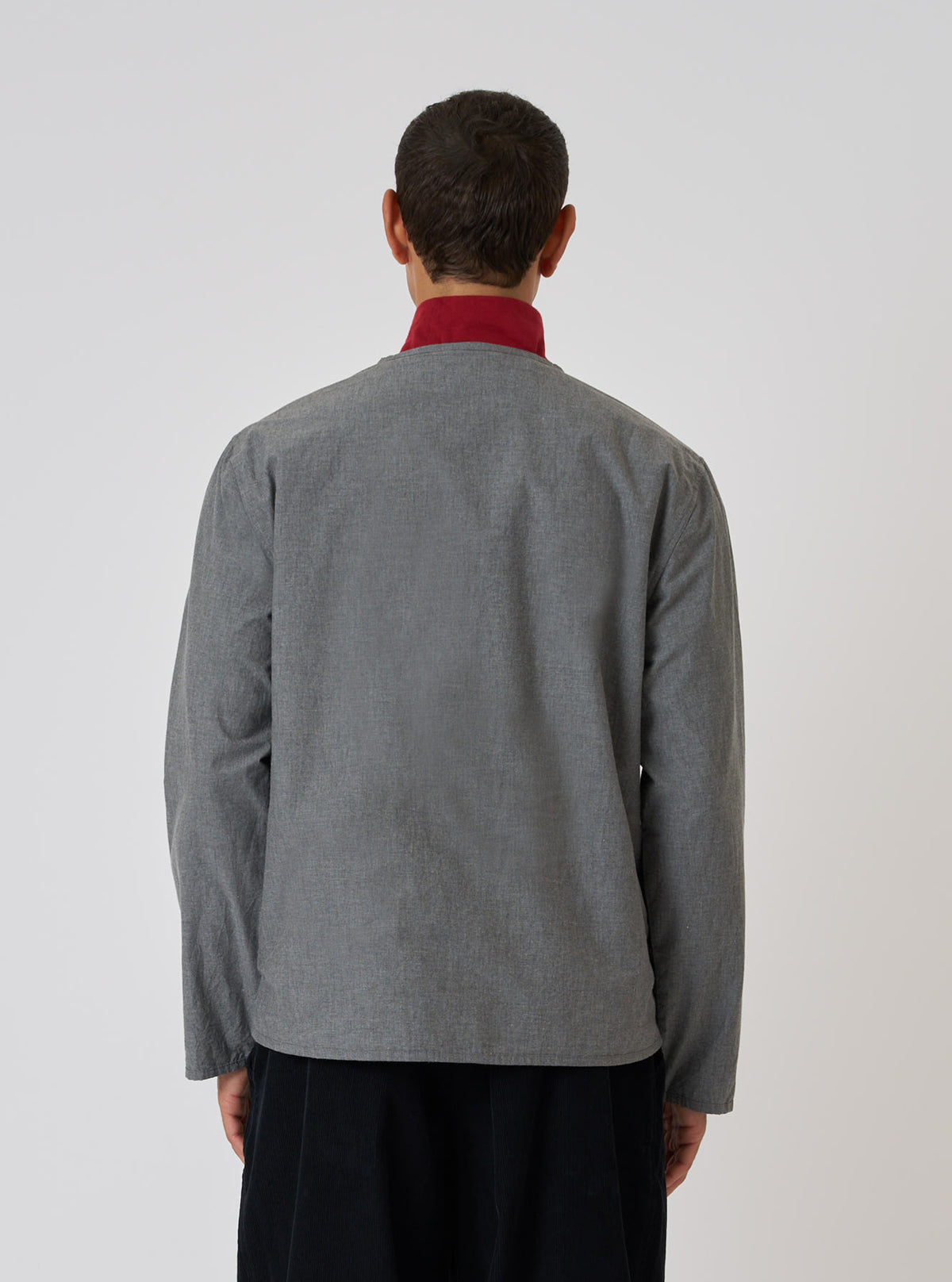Back view of a model wearing the Charcoal Organic Chambray Parachute Liner Jacket. The jacket is gray with a red collar, set against a plain white background.