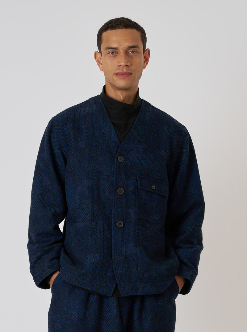 A model poses in front of a white background wearing the Black/Indigo Denim Camo Cabin Jacket. The jacket is indigo with a subtle camo pattern.
