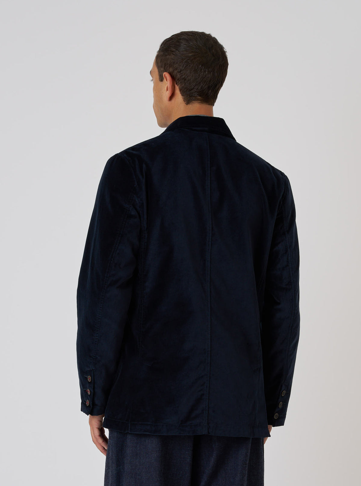 Back view of a model wearing a Navy Velveteen Manor Jacket. The jacket is a rich navy color and has a classic fit. Shot against a plain white background.