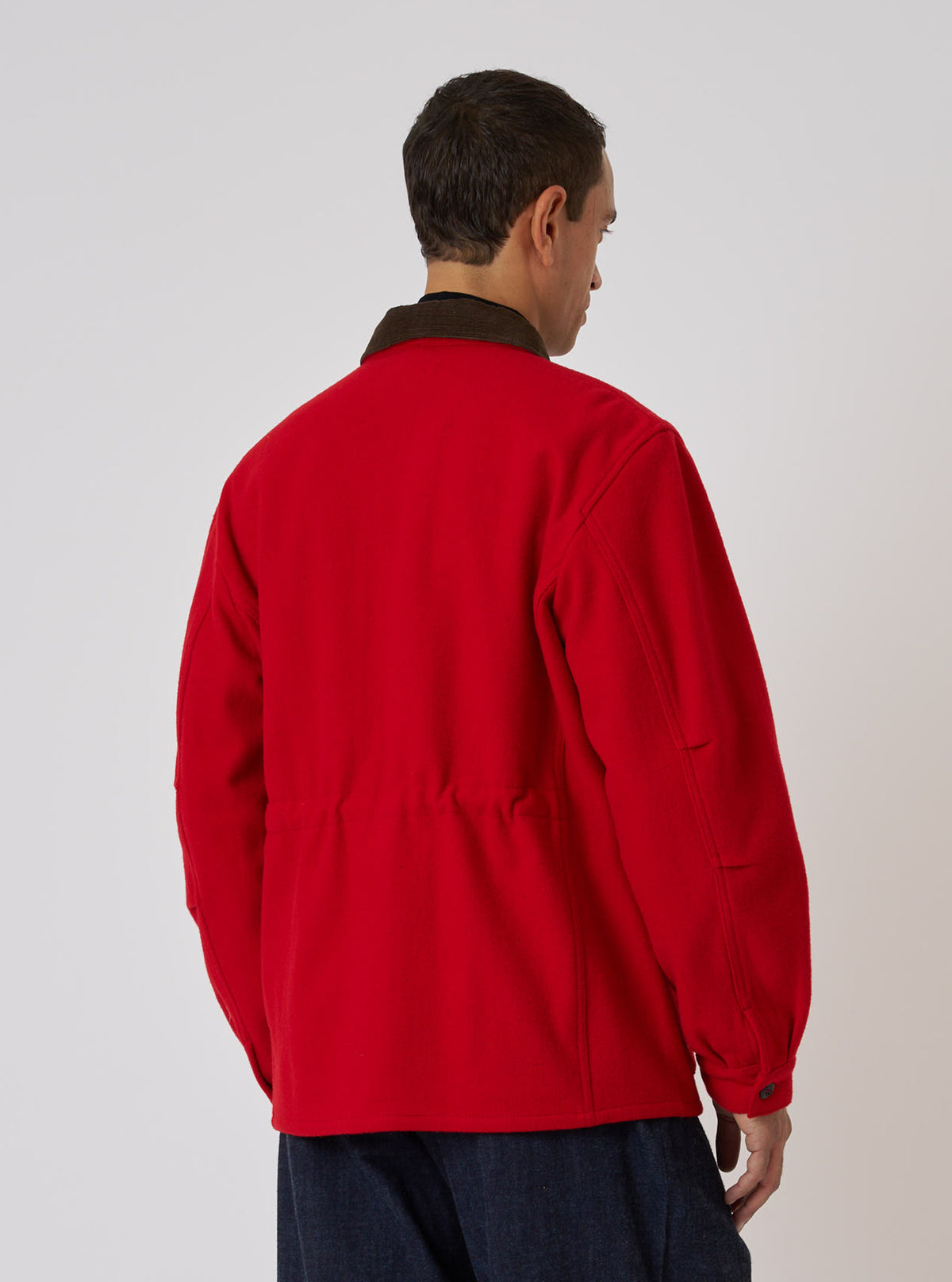 Back view of a model wearing a Red Mowbray Military Fatigue Jacket. The jacket is bright red with a brown corduroy collar. Shot against a plain white backdrop.