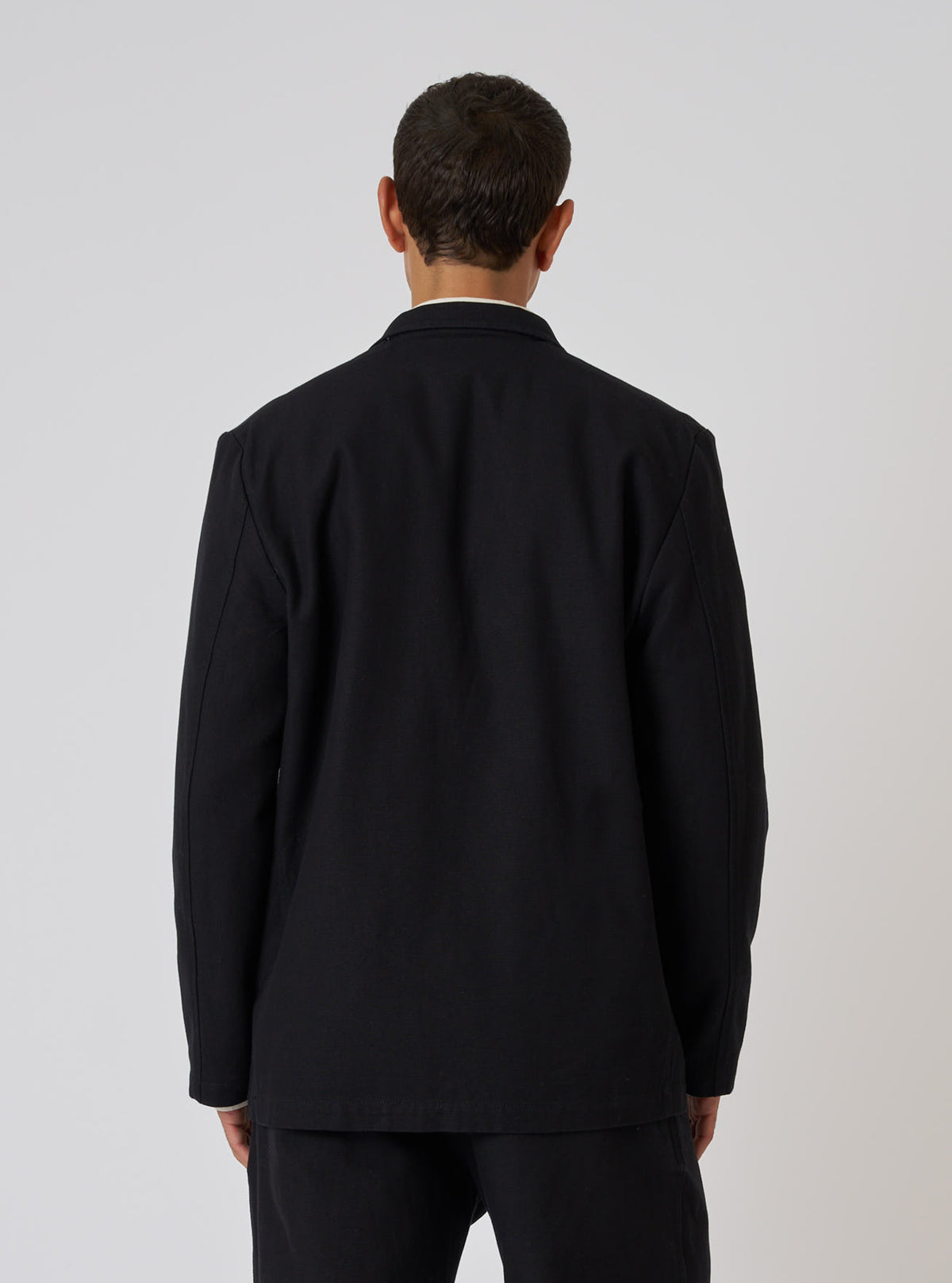 Back view of a model wearing a Black Organic Canvas Two Button Jacket. The jacket is on a white background.