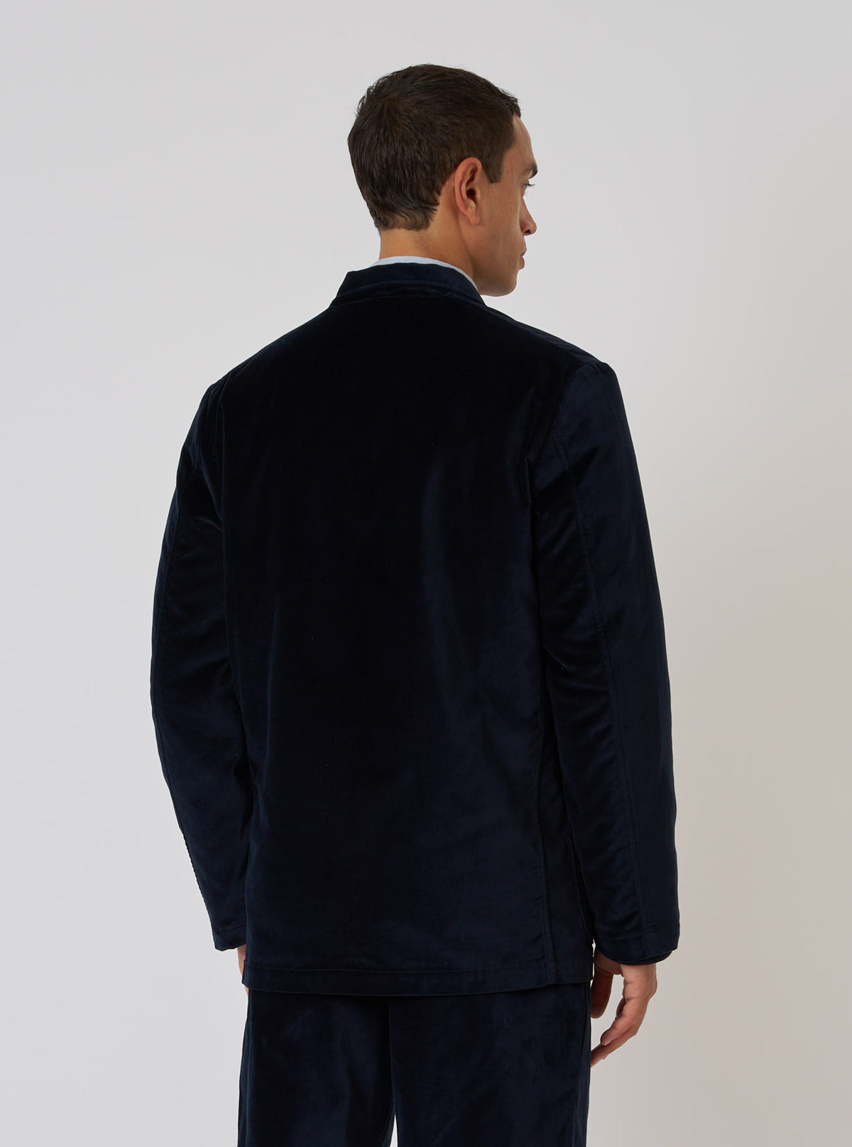 Back view of a model wearing a Navy Velveteen Two Button Jacket in front of a plain white background. The jacket is a rich navy color and appears soft.