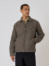 A model wears the Sand Cortina Tweed Windcheater, a brown and black tweed jacket, against a plain background. The jacket has a zip front and pockets.