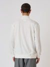 Back view of a model wearing an Ecru Single Jersey Funnel Neck Tee. The tee is a light cream color and has long sleeves. The background is a plain white studio backdrop.