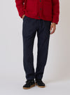 Studio shot of a model wearing Indigo Brushed Denim Military Chino, paired with a red jacket and black sneakers. The background is a clean, light color.