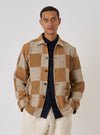 A model poses in a Sand Japanese Patchwork Easy Jacket. The jacket has a tan and cream checkerboard pattern. He wears a navy shirt and cream pants against a plain white backdrop.