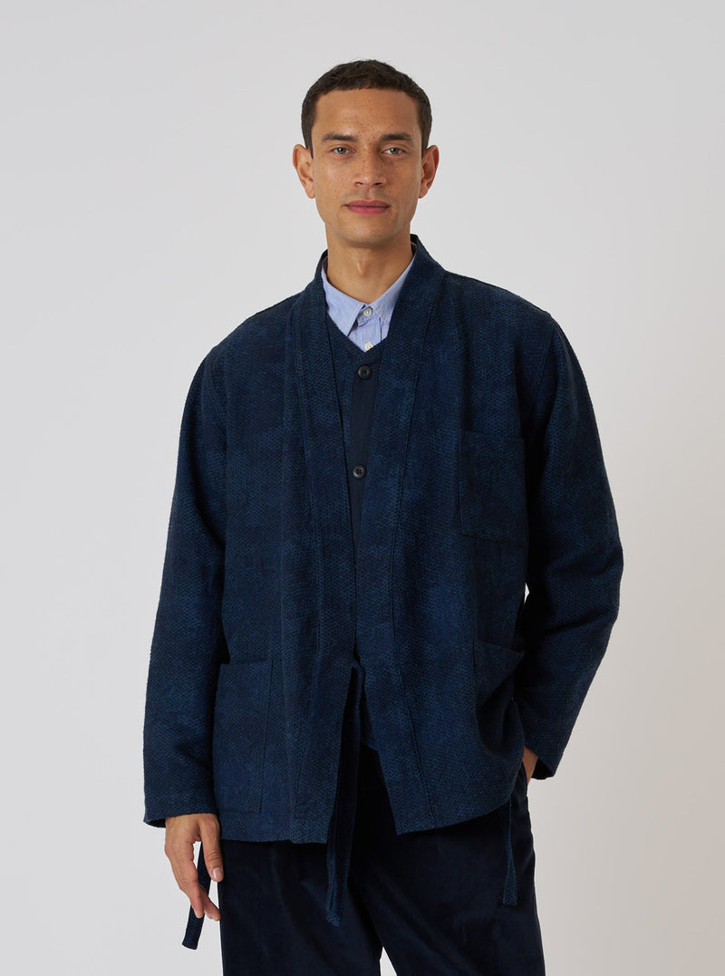A man poses in front of a white background, wearing the Black/Indigo Denim Camo Kyoto Work Jacket. The jacket is a dark blue denim with a subtle camo pattern.