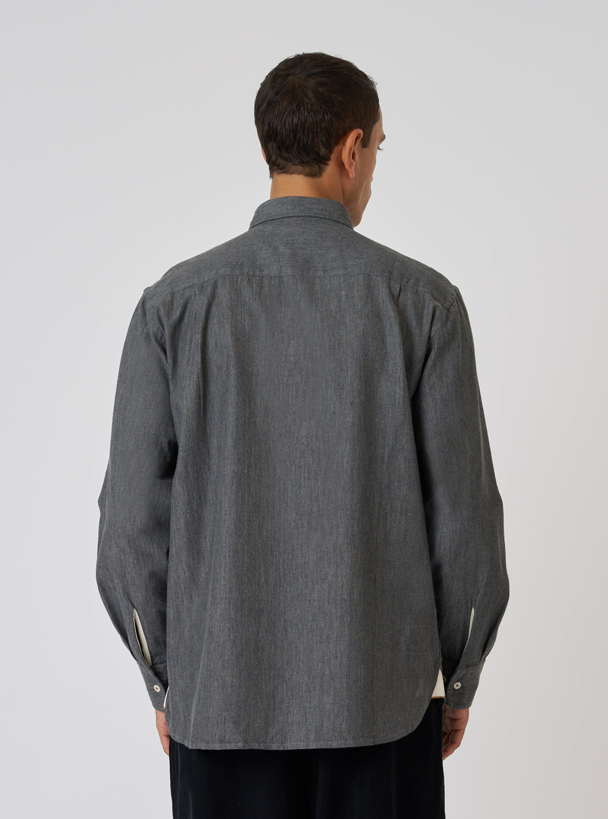 Back view of a model wearing a Charcoal Brushed Organic Cotton Square Pocket Shirt. The shirt is charcoal gray and made of organic cotton. The background is a plain white.