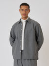 A model poses in a Charcoal Organic Chambray Lucky Shirt and matching pants against a white backdrop. The shirt is a relaxed fit with a button-down front.